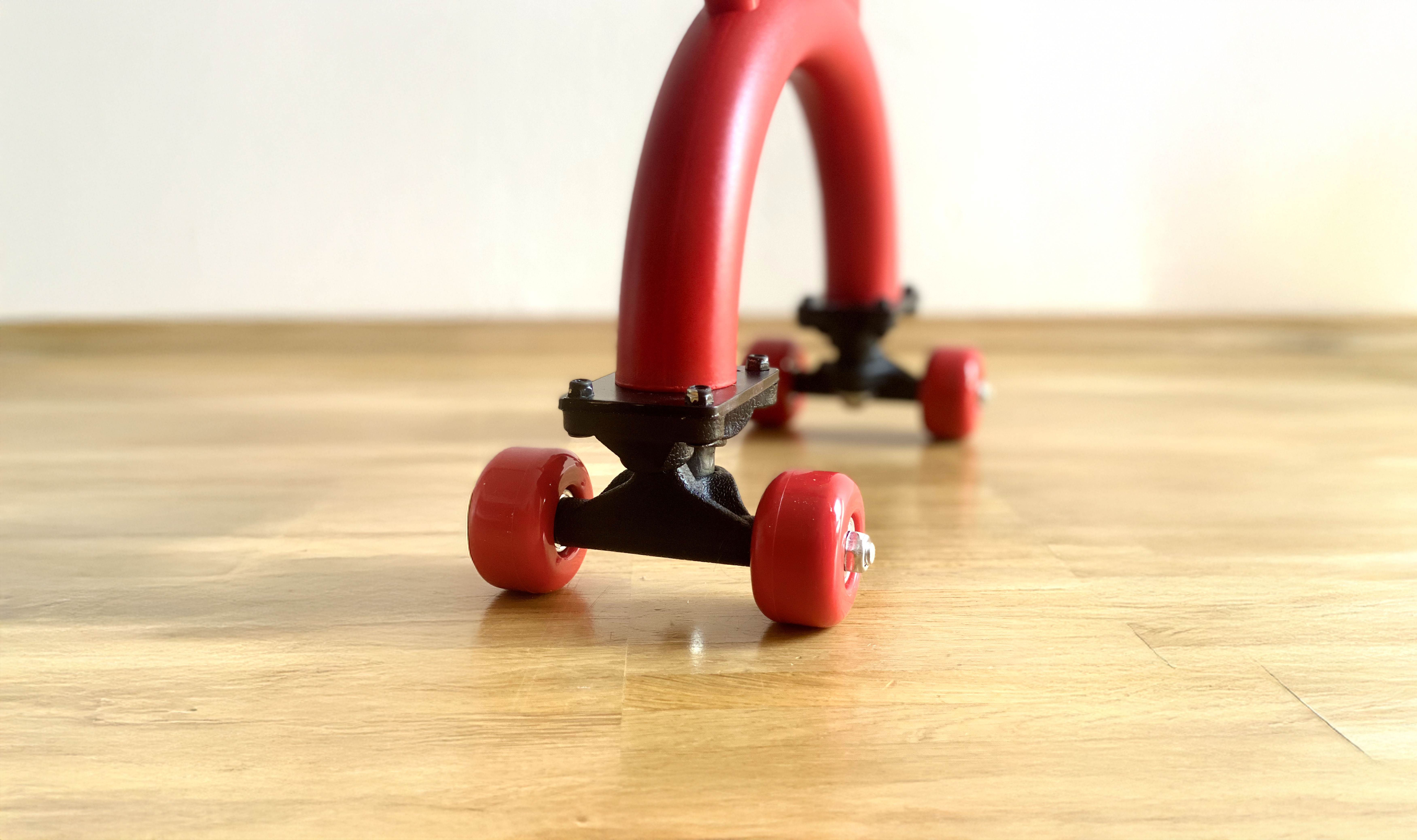 Nahaufnahme der Räder des roten Sideboards auf einem Holzboden