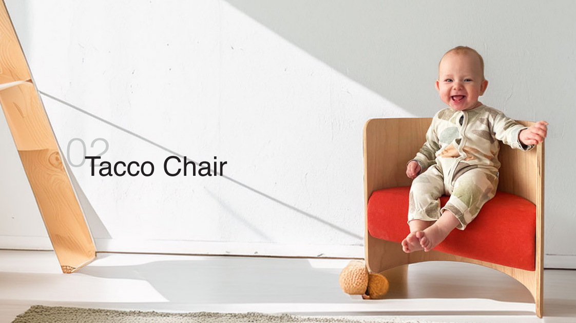 Ein lächelndes Baby sitzt in einem modernen hölzernen Tacco Chair